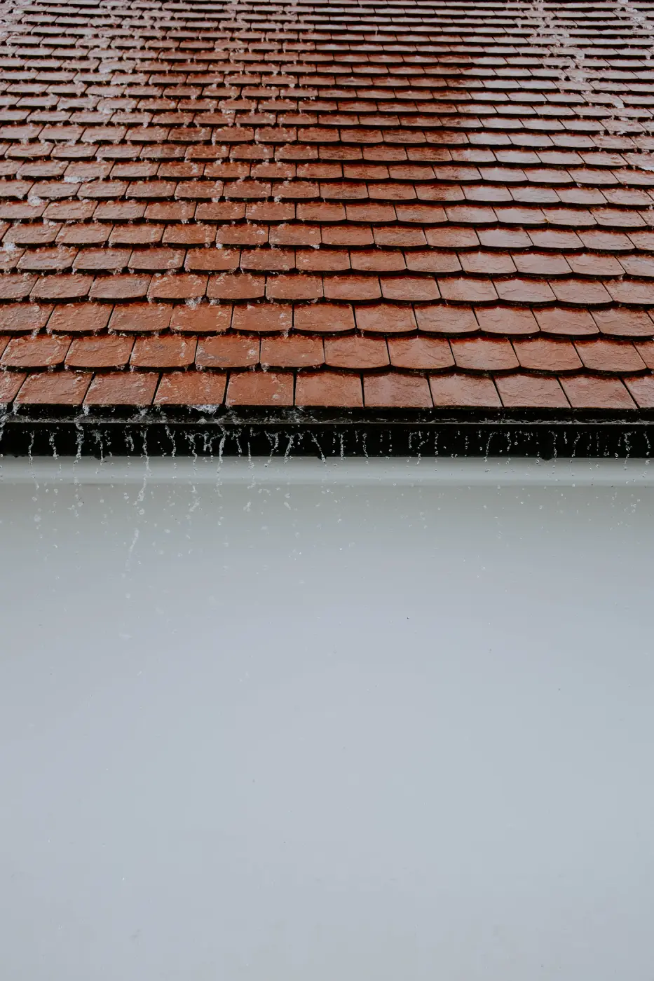 Regenwater dat van de rand van een pannendak loopt