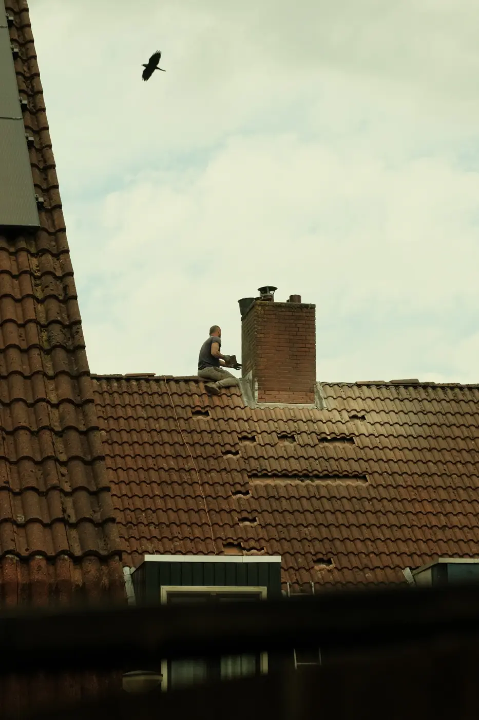 Dakdekker op een pannendak naast de schoorsteen
