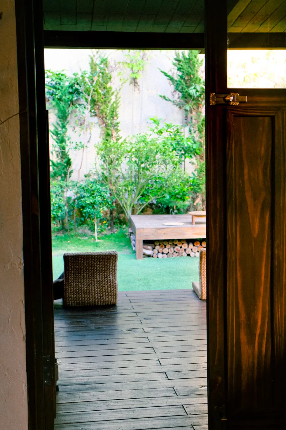 Doorkijk door een open houten deur naar een vlonder en de tuin