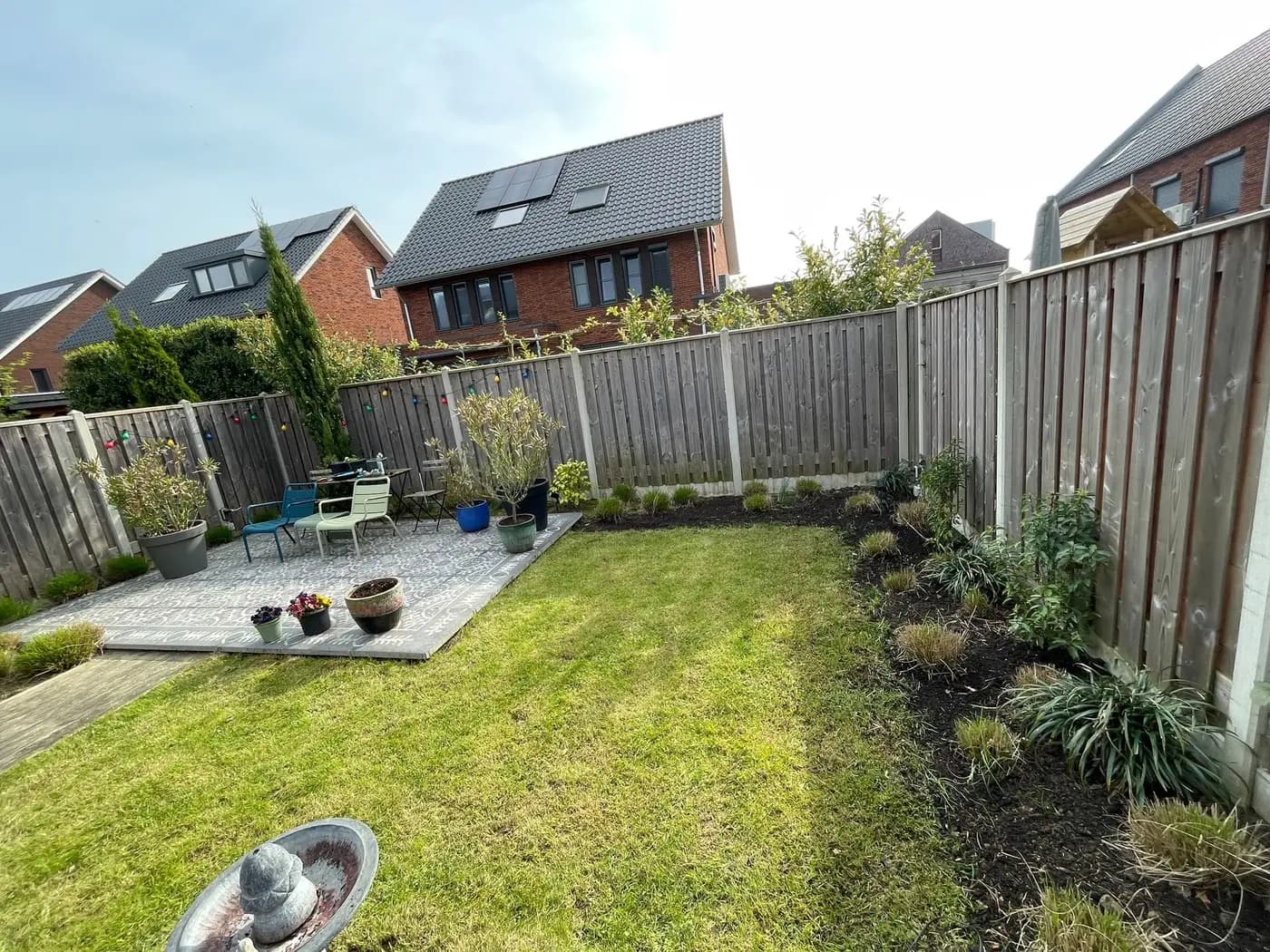 Aangelegde achtertuin met gazon, een border en een keramisch terras